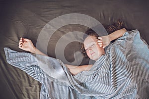 Beautiful young woman lying down in bed and sleeping, top view. Do not get enough sleep concept