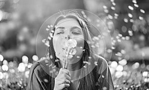 Beautiful Young Woman lying on the field in grass and blowing dandelions. Outdoors