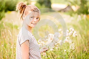 Beautiful Young Woman lying on the field in green grass and blowing dandelion. Outdoors. Enjoy Nature. Healthy Smiling Girl on spr