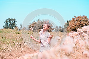 Beautiful Young Woman lying on the field in green grass and blowing dandelion. Outdoors. Enjoy Nature. Healthy Smiling Girl on spr