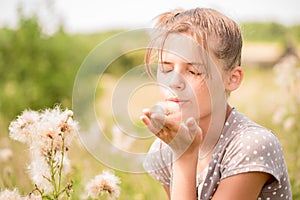 Beautiful Young Woman lying on the field in green grass and blowing dandelion. Outdoors. Enjoy Nature. Healthy Smiling Girl on spr