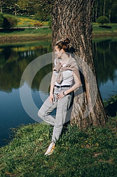 Beautiful Young Woman lying on a field, green grass and dandelion flowers. Outdoors Enjoy Nature. Healthy Smiling Girl lying in