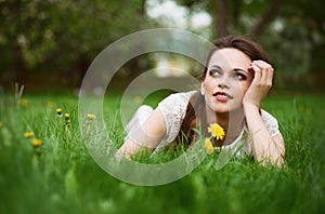 Beautiful young woman lying in green grass