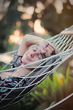 Beautiful young woman lying in a hammock and relaxing with close