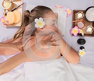 Beautiful young woman lying and relaxing with body massage and treatment in spa salon