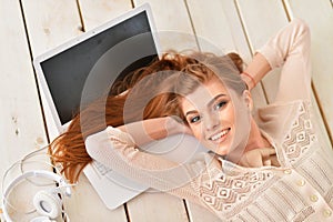 Beautiful young woman lying on wooden floor