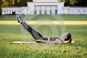 Beautiful young woman lying on a yellow mattress doing pilates or yoga, the hundred intermediate exercises