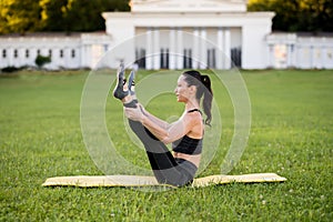 Beautiful young woman lying on a yellow mattress doing pilates or yoga, one leg rocker expert exercises