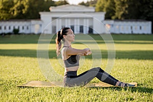 Beautiful young woman lying on a yellow mattress doing pilates or yoga, spine twist beginner exercises