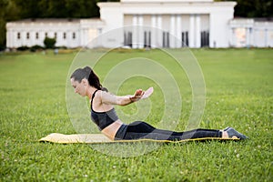 Beautiful young woman lying on a yellow mattress doing pilates or yoga, swan dive expert exercises