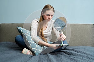 Beautiful young woman with make-up mirror sitting at home in bed