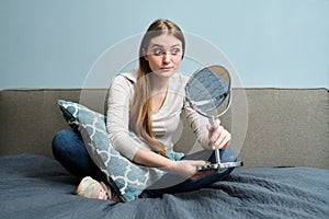 Beautiful young woman with make-up mirror sitting at home in bed