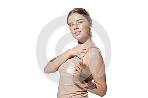 Beautiful young woman massaging her skin with moisturizer over white background. Cosmetics and makeup, natural and eco