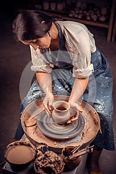 Beautiful young woman master demonstrates the process of making ceramic dishes using the old technology. Handwork.