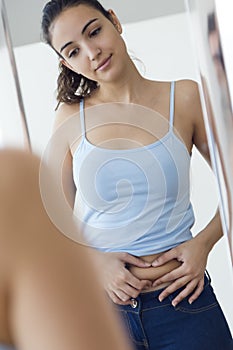 Beautiful young woman measuring fat level on her abdominal.