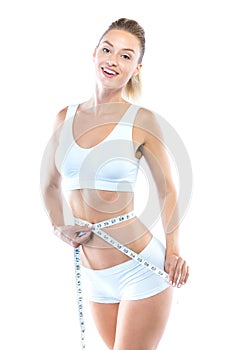 Beautiful young woman measuring her slim body over white background.
