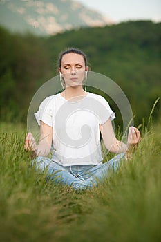 Beautiful young woman meditate on meadou na early summer evening