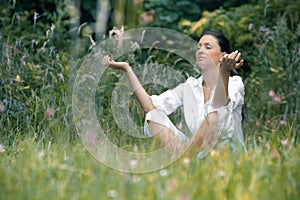 Beautiful young woman meditating on field