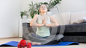 Beautiful young woman meditating and practicing yoga at home