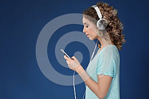 Beautiful young woman with mobile phone listening to music on color background