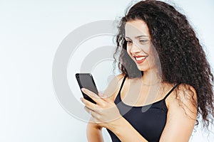 Beautiful young woman model with curly hair using a smartphone