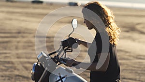 Beautiful young woman motorcyclist with his girlfriend riding a motorcycle in a desert on sunset or sunrise. Girlfriends on a bike