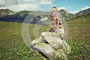 Beautiful young woman in mountains on a meadow