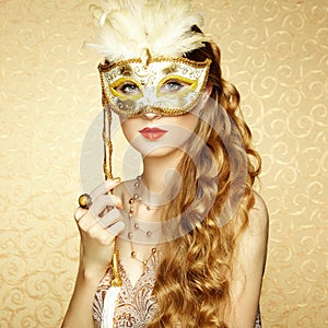 Beautiful young woman in mysterious golden Venetian mask photo