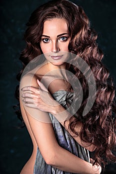 Beautiful young woman with natural make-up and hair style posing naked covering with grey cloth