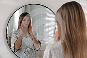 Beautiful young woman near mirror in room