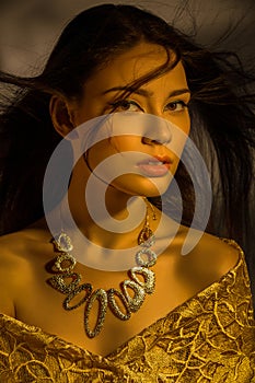 Beautiful young woman with necklace in golden light
