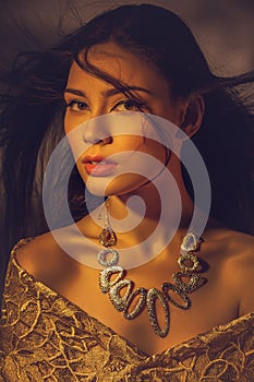 Beautiful young woman with necklace in golden light