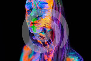 Beautiful young woman in neon light. Portrait of a model with fluorescent makeup posing in UV light with colorful makeup