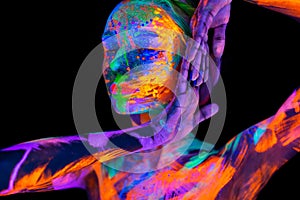 Beautiful young woman in neon light. Portrait of a model with fluorescent makeup posing in UV light with colorful makeup