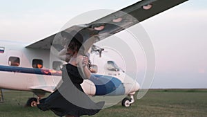 Beautiful young woman next to the plane. Portrait of a beautiful smiling woman in a hat and black dress. young woman in