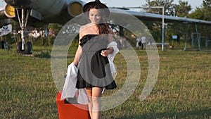 Beautiful young woman next to the plane. Portrait of a beautiful smiling woman in a hat walking at the airport on the