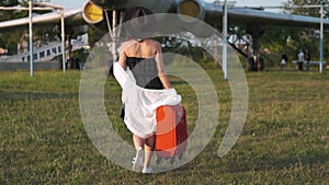 Beautiful young woman next to the plane. Portrait of a beautiful smiling woman in a hat walking at the airport on the