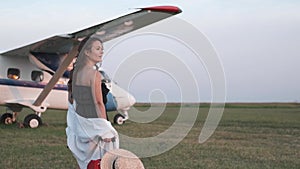 Beautiful young woman next to the plane. Portrait of a beautiful smiling woman in a hat walking at the airport on the