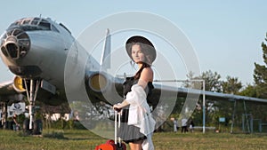 Beautiful young woman next to the plane. Portrait of a beautiful smiling woman in a hat walking at the airport on the