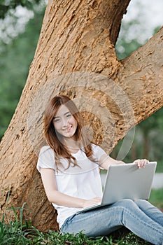 Beautiful young woman using laptop sitting in the park