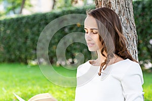 Beautiful young woman with notepad in park