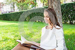 Beautiful young woman with notepad in park