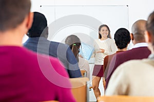 Beautiful young woman offering product for sale in front of chalkboard
