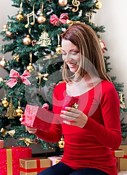 Beautiful young woman opening a Christmas present