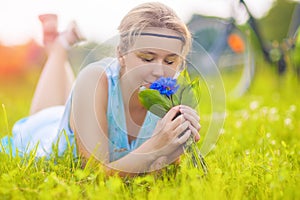 Beautiful Young Woman Outdoors. Calm Relaxing Girl on Green Grass Smelling Flowers Bouquet