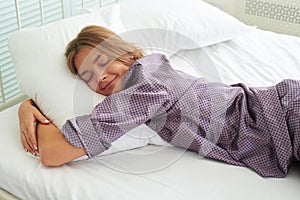 Beautiful young woman in pajamas sleeping and hugging the pillow