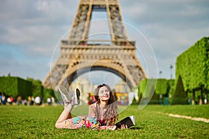 Beautiful young woman in Paris lying on the grass near the Eiffel tower