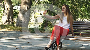 Beautiful young woman on a Park bench taking a selfie