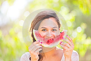 Beautiful young woman at park eating a slice of watermelon