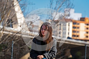 Beautiful young woman in a park wearing glasses and a grey coat